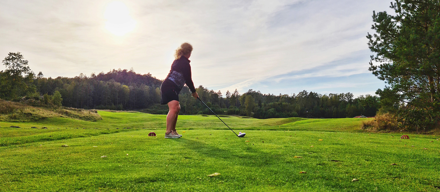Kvinna som spelar golf utomhus.